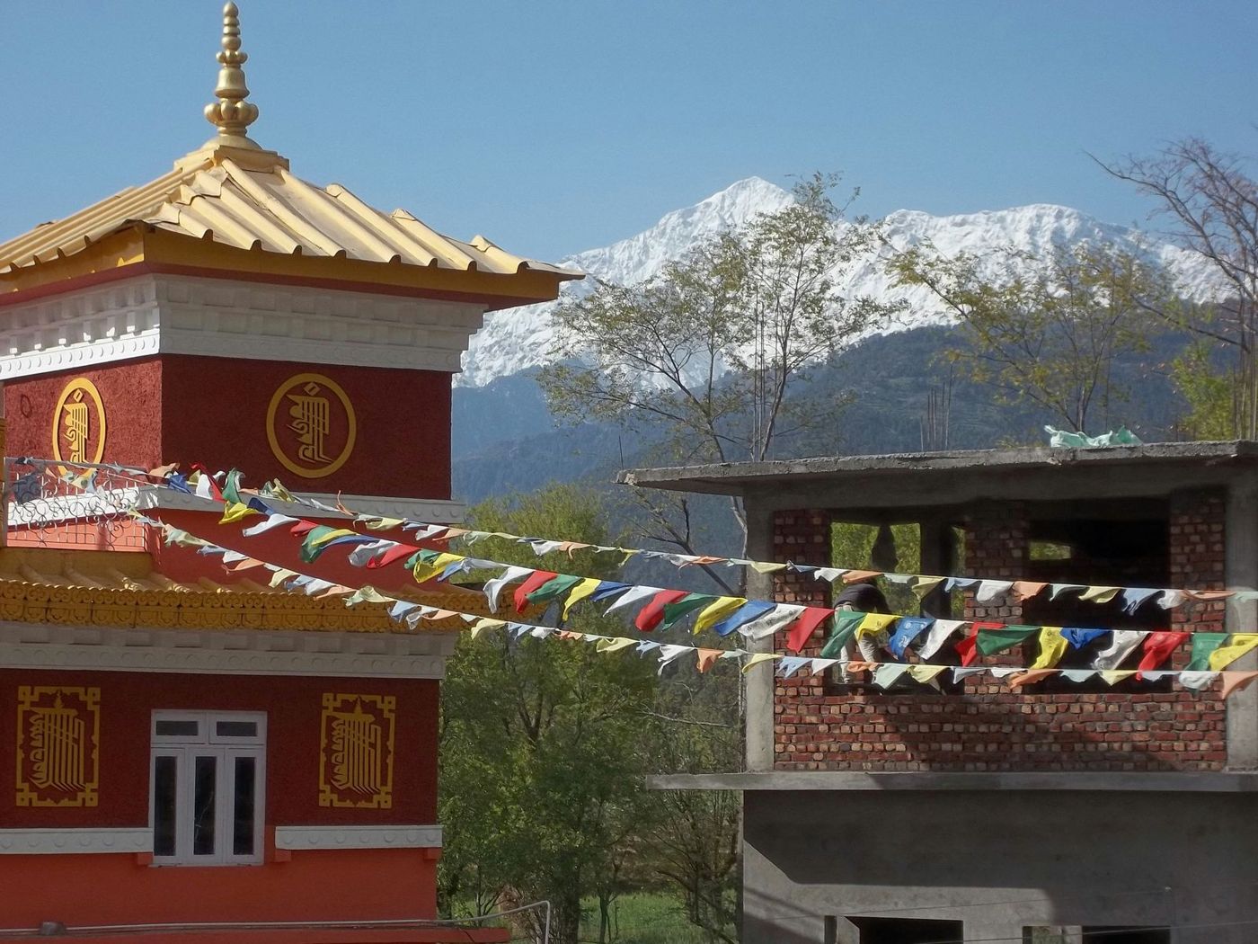 Tibetská stavba s modlitebnými vlajkami a zasneženým štítom