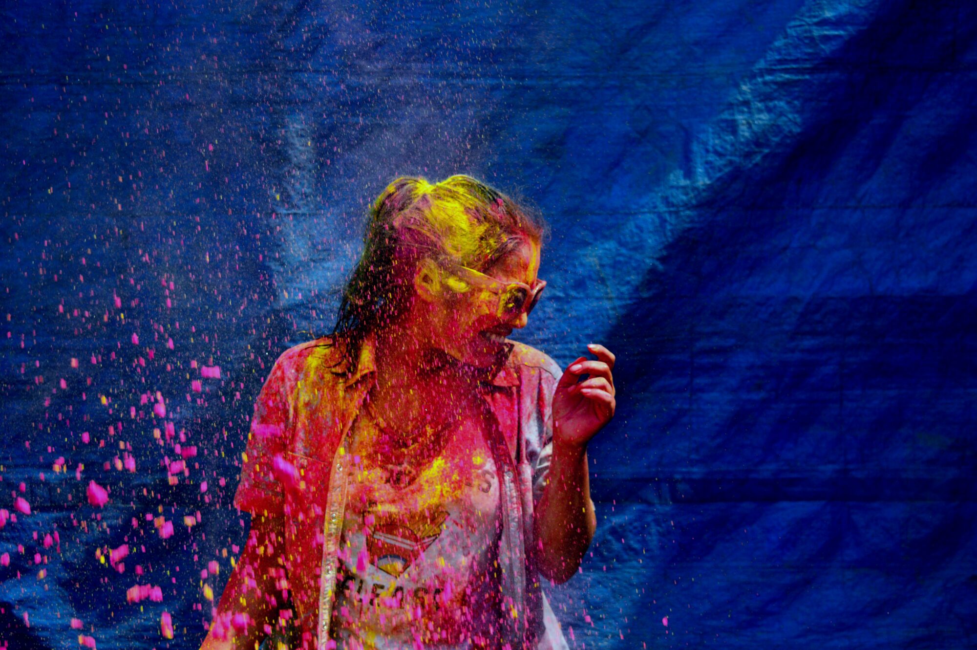 Žena zasypaná farebným prachom počas sviatku Holi